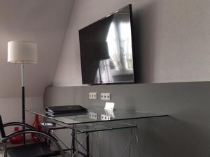 a glass table with a television on a wall at Das Goldene Lamm Aalen in Aalen