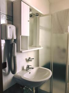 ein Bad mit einem Waschbecken, einer Dusche und einem Telefon in der Unterkunft Hotel Ristorante Gallo D'Oro in Vignola