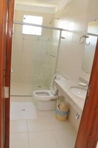 a white bathroom with a toilet and a sink at Beija - Flor Hotel in Ipiaú