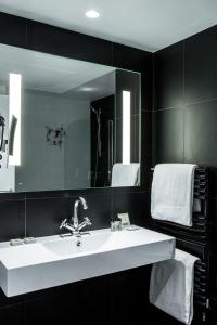 a white sink sitting under a mirror in a bathroom at Le Général Hôtel in Paris