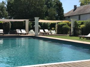 a swimming pool with chairs and a pergola at Le Pavillon du Château, Hôtel & SPA in Revel
