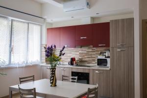 a kitchen with red cabinets and a table with a vase of flowers at Family Apartment London in Verona