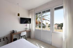 a bedroom with a desk and a sliding glass door at Hôtel Les Voiles in Toulon