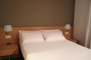 
a bed with a white comforter and pillows at Hostal Abodi in Pamplona
