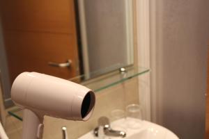 baño con dispensador de papel higiénico y lavamanos en Hostal Abodi en Pamplona