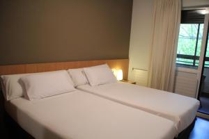a large white bed in a room with a window at Hostal Abodi in Pamplona +8 photos