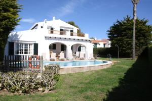 a white house with a swimming pool in front of it at Villa Binigo in Binibeca