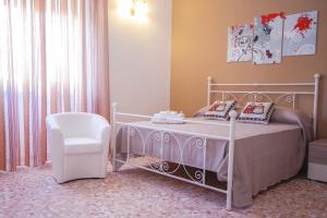 a bedroom with a white bed and a chair at La Fenice Salentina in Alezio
