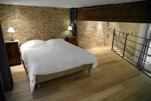 a bedroom with a white bed and a brick wall at Atout Carmes in Toulouse