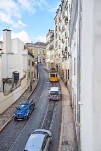 tre auto su binari in una città con un treno di Modern Apartment Calçada São Francisco II a Lisbona