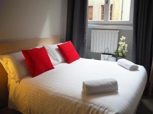 ein Bett mit roten und weißen Kissen und einem Fenster in der Unterkunft Hotel Centro in Florenz