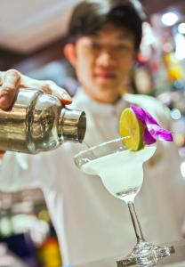 a person pouring a drink into a martini glass at Classy Holiday Hotel & Spa in Hanoi +35 photos