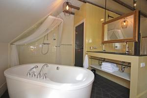 a bathroom with a large tub and a mirror at B&B Lhee-Gaarde in Dwingeloo