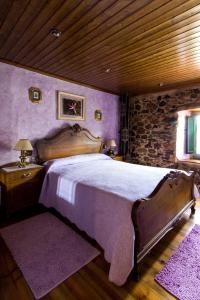 ein Schlafzimmer mit einem großen Bett und einer Steinmauer in der Unterkunft Paraíso Ortegal in Feás