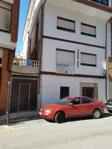 圣维森特-德拉巴尔克拉Hostal Arenal的一辆红色汽车停在一栋建筑物前