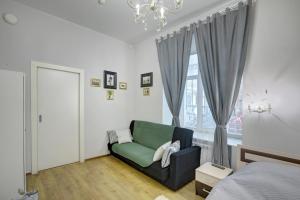 a bedroom with a green couch in front of a window at Apartments Logic Hall in Saint Petersburg