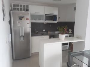 una cocina con nevera de acero inoxidable y armarios blancos en Departamento En Tigre en Tigre