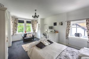 a bedroom with a bed and a chair and windows at Halmer Grange Guest House in Goathland