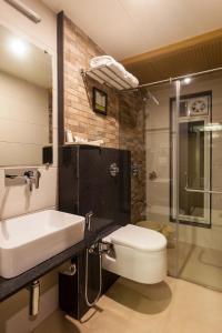 ein Bad mit einem Waschbecken, einem WC und einer Dusche in der Unterkunft Hotel Chaitali - Pure Veg in Kolhapur