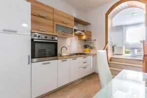 Boban Sunny Apartment في سولين: مطبخ مع دواليب بيضاء وطاولة زجاجية