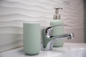 - un lavabo dans la salle de bains avec distributeur de savon à côté d'un robinet dans l'établissement La dimora di Clara, à Trapani