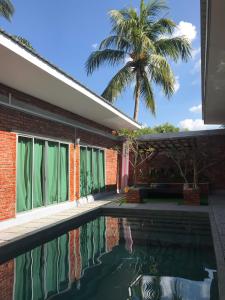 a house with a swimming pool and a palm tree at Tanjung Rhu Pool Villa @ TRV in Huma