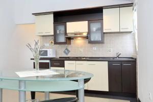 a kitchen with white cabinets and a glass table at Apartmani Mlinar in Gornji Karin