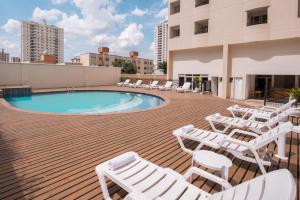 una terraza con sillas blancas y una piscina en un edificio en Blue Tree Towers All Suites Santo André, en Santo André