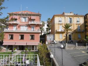 un edificio rosa accanto a due edifici più vecchi di Hotel Villa Maria a Sanremo