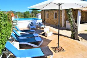 un grupo de sillas azules y una sombrilla junto a una piscina en Es Marroig, en Llucmajor