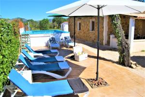 a group of blue chairs and an umbrella next to a pool at Es Marroig Villa y Spa in Llucmajor
