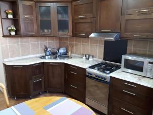 a kitchen with wooden cabinets and a stove and microwave at Apartment Archil Batumi in Batumi