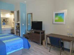 a hotel room with a bed and a desk and a television at Hotel Blue - Woodlands in Spring