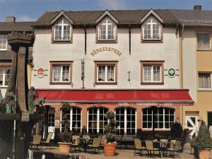 a building with tables and chairs in front of it at Hotel Restaurant Bürgerstube in Ulmen