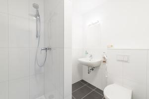 een witte badkamer met een douche en een wastafel bij Pension Kreidefels in Sassnitz