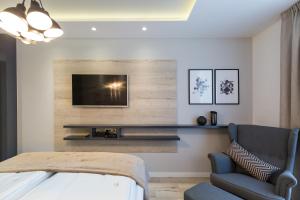 ein Wohnzimmer mit einem TV, einem Sofa und einem Stuhl in der Unterkunft Classy Design Accommodation in Zadar