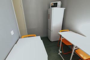 モスクワにあるHostel on Nakhimovsky prospektの小さなお部屋で、テーブル2台、冷蔵庫が備わります。