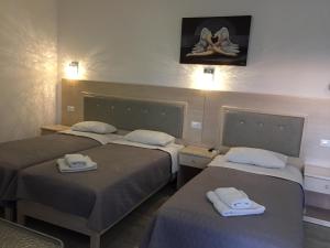- une chambre avec 3 lits et des serviettes dans l'établissement Diogenis Village Mykonos, à Glastros