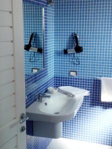 Baño de azulejos azules con lavabo y espejo en B&B Conca del Faro, en Mattinata