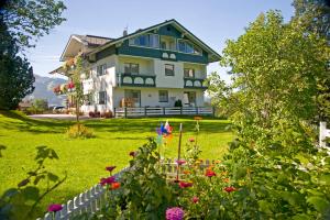 duży dom z kwiatami w ogródku w obiekcie Landhaus & Ferienwohnungen Bergrast w mieście Ramsau am Dachstein