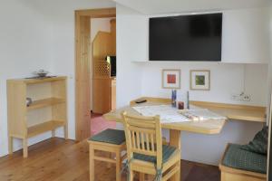 ラムサウ・アム・ダッハシュタインにあるLandhaus & Ferienwohnungen Bergrastのデスク、壁掛けテレビが備わる客室です。