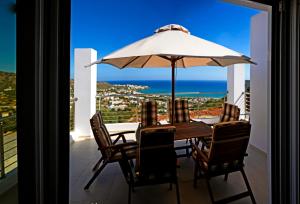 a table and chairs with an umbrella on a balcony at Villa Xenia Stalis in Stalís