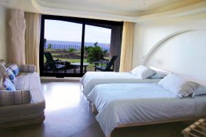 a hotel room with two beds and a couch and a window at Nayara Hangaroa in Hanga Roa
