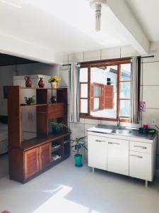 cocina con armarios blancos, fregadero y ventana en Lagoa da Conceição Apartments, en Florianópolis