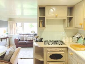 a kitchen with a stove and a living room at Estuary View Caravans in Alnmouth
