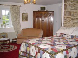 1 dormitorio con 1 cama y 1 silla en Holdstrong Farmhouse, en Lydford