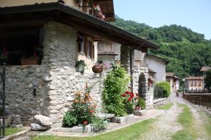 a stone house with flowers on the side of it at Il Giardino degli Elfi in Forno D'ono