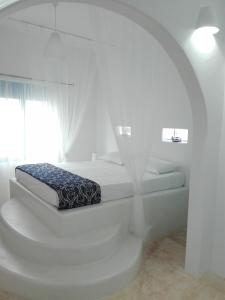 a white bedroom with a bed and a window at Tilos Island house in Megálon Choríon