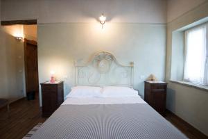 ein Schlafzimmer mit einem großen weißen Bett mit zwei Nachttischen in der Unterkunft Agricola casa cucina bottega in Cesena