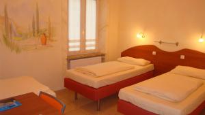 1 dormitorio con 2 camas, mesa y ventana en StadtHotel Passau, en Passau